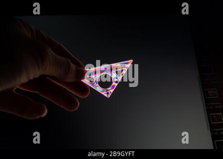 Persona che dimostra la polarizzazione incrociata con un set quadrato di plastica trasparente, fotografata attraverso un filtro polarizzante con una sorgente di luce polarizzata. Foto Stock