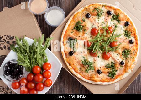 Consegna pizza con salmone e rucola in scatola di cartone Foto Stock