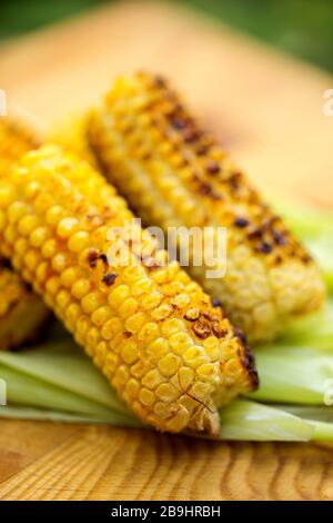 Pannocchie di mais dolce alla griglia su legno rustico Foto Stock