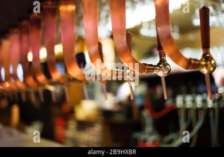 Birra alla spina nel pub belga. Rubinetti per birra di rame. Profondità di campo bassa Foto Stock