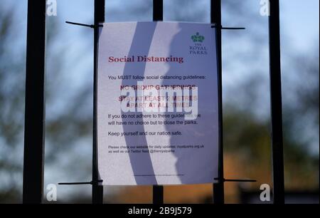 Un segnale relativo alle distanze sociali sulle porte di Richmond Park, il giorno dopo che il primo ministro Boris Johnson ha messo il Regno Unito in blocco per contribuire a frenare la diffusione del coronavirus. Foto Stock