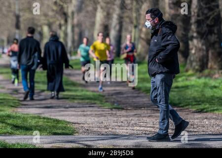 Clapham Common, Londra, Regno Unito. 24 Marzo 2020. Joggers mescolare con gli escursionisti - la gente esce sul Clapham comune per ottenere i loro giorni di esercizio in - la maggior parte pratica sociale a distanza, ma è quasi occupato come un normale giorno di primavera. Il primo giorno dell'epidemia di "blocco" a Clapham - Anti Coronavirus (Covid 19) a Londra. Credit: Guy Bell/Alamy Live News Foto Stock