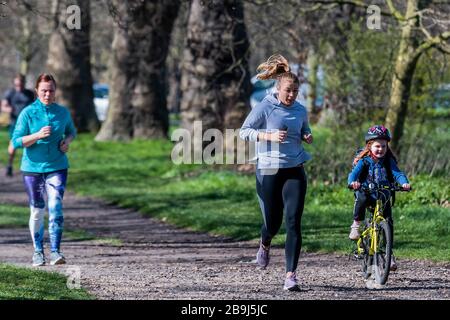 Clapham Common, Londra, Regno Unito. 24 Marzo 2020. Joggers mescolare con gli escursionisti - la gente esce sul Clapham comune per ottenere i loro giorni di esercizio in - la maggior parte pratica sociale a distanza, ma è quasi occupato come un normale giorno di primavera. Il primo giorno dell'epidemia di "blocco" a Clapham - Anti Coronavirus (Covid 19) a Londra. Credit: Guy Bell/Alamy Live News Foto Stock