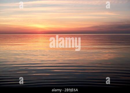 Sole sopra l'acqua attraverso le nuvole con ondulazione diritta in acqua Foto Stock