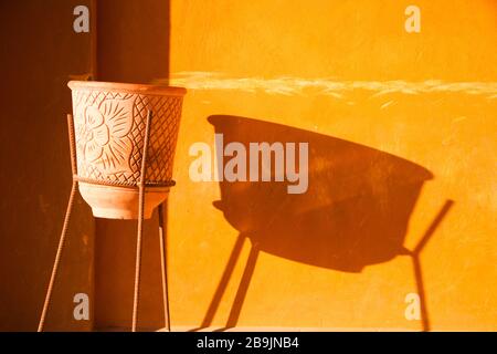 Terracotta Flower Pot casting a Long Shadow on Orange Mura in El Gouna Egitto Foto Stock