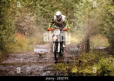 motocross enduro corsa atleta su sentiero fangoso e bagnato in foresta Foto Stock