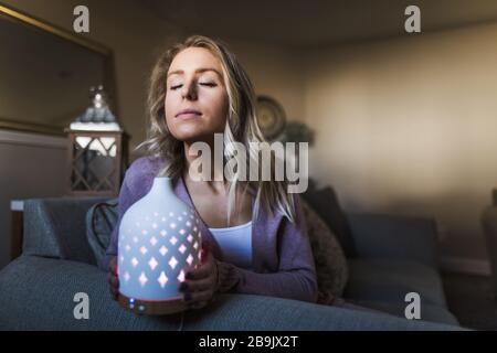 Giovane donna che odora il suo diffusore essenziale dell'olio Foto Stock