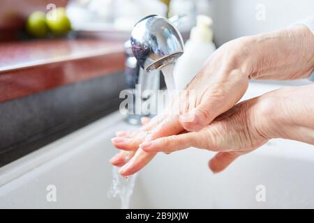 Donna anziana lavando le mani con sapone come protezione contro l'infezione all'epidemia di coronavirus Foto Stock