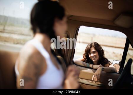 Donna seduta in un camion pick-up, parlando con il suo amico che è appoggiato alla finestra. Foto Stock