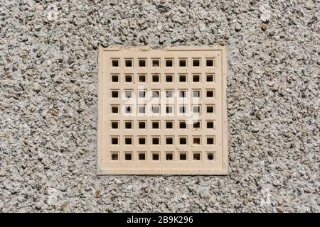 Pavimento in cotto chiaro per ventilazione aria sul lato di un muro di pietra tratteggiato. Metafora foro rotondo pioli quadrato. Foto Stock