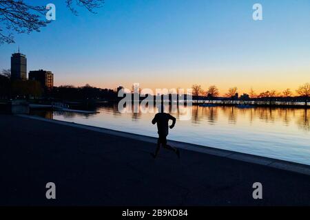 Un uomo al tramonto corre lungo il fiume Charles a Boston. Foto Stock