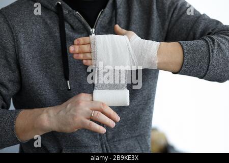 L'uomo si dona come primo soccorso nastro di bendaggio arrotolabile sopra il polso Foto Stock