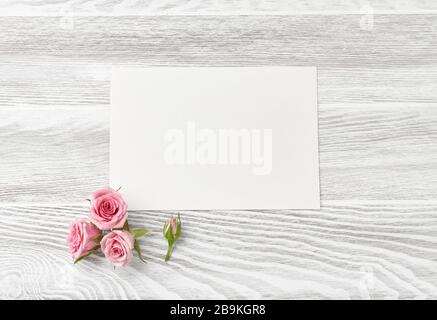 Area di lavoro per fioristi fiori rosa cesoie carta da imballaggio e  disposizione delle foglie su sfondo bianco con spazio per la copia