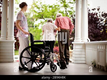 Nurse guarda la donna anziana assistere suo marito a piedi. Foto Stock