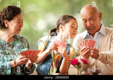 Coppia senior giocando a carte con loro nipote. Foto Stock