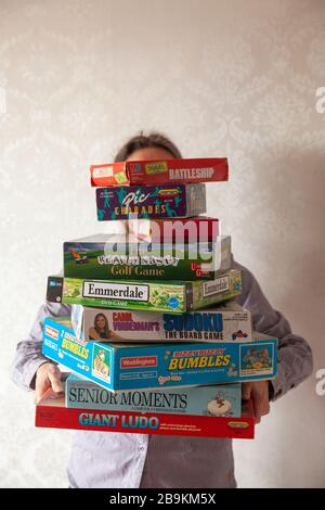 Una persona che detiene una grande collezione di giochi da tavolo Foto Stock