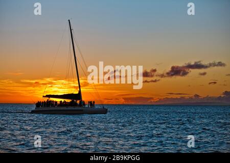 Silhouette di persone su una barca a vela godendo del tramonto al mare. Foto Stock