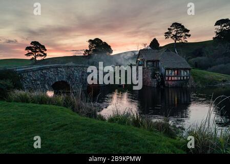 Tramonto sul ponte e mulino presso il set cinematografico di Hobbiton, Nuova Zelanda Foto Stock