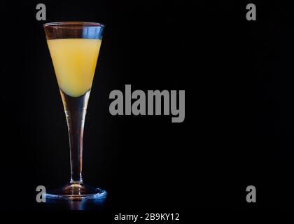 Limoncello in elegante vetro liquoroso su sfondo scuro. Chiaroscuro. Liquore al limone siciliano, aromatico e rinfrescante. Foto Stock