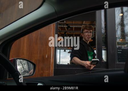 Il cassiere effettua il pagamento attraverso una vetrina di auto in una guida Starbucks, nel Regno Unito Foto Stock