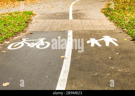 Simboli e marcature su un percorso che evidenziano corsie separate per ciclisti e persone che camminano Foto Stock