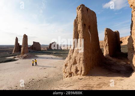 Madre e figlio a rovine mozzafiato di Jampik Kala fortezza situata Kyzylkum deserto nella regione di Karakalpakstan in Uzbekistan Foto Stock