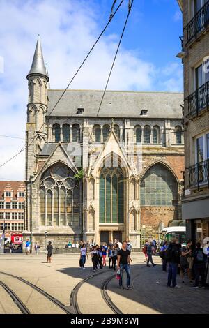 Immagine verticale del lato della chiesa di San Nicola con i binari del tram e i turisti in una giornata di sole con le nuvole. Foto Stock