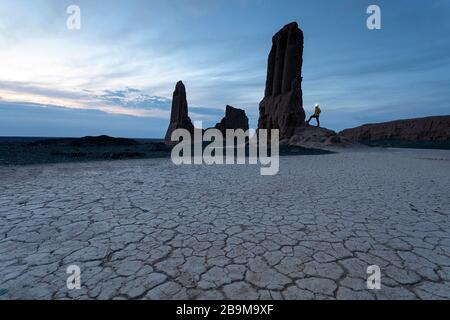 Donna con un faro leggero in piedi alle rovine mozzafiato della fortezza di Jampik Kala situato nel deserto di Kyzylkum nella regione di Karakalpakstan in Uzbekistan Foto Stock