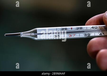 Uomo tenere un termometro di febbre da mercurio dopo la misurazione,  coronavirus covid19 pandemica Foto stock - Alamy