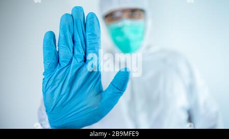 Medico caucasico maschio che indossa un vestito protettivo e maschera, facendo stop segno gesto, saysigning No. Rifiuto della malattia del virus, primo piano. Isolato su whi Foto Stock