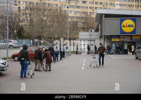 Bucarest, Romania - 24 marzo 2020: La gente aspetta in linea di fronte ad un supermercato Lidl, dopo che un blocco di Coronavirus è annunciato. Foto Stock