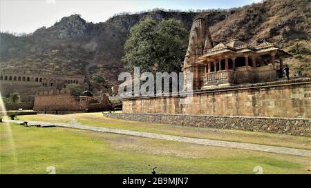 Vista remota di luce del forte di nahargarh rovinato con il tempio impressionante all'ingresso situato a Jaipur, Rajasthan, India Foto Stock