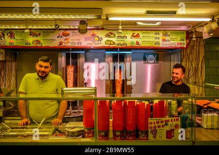 Berlino, Germania 02/02/20: Due persone sorridono ad un Doner Kebap fast food. Negozio turco nella metropolitana U-Bahn della stazione Alexanderplatz con 2 lavoratori felici Foto Stock