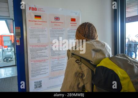 Berlin Schonefeld Airport SXF, Germany - 02/01/20: Avviso pubblico su Coronavirus 2019-nCoV nel terminal dell'aeroporto letto da un viaggiatore. Foto Stock