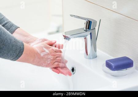 Lavaggio a mano con sapone sopra il lavandino in bagno, closeup. Foto Stock