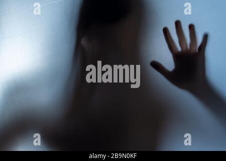 Offuscata ombra della mano della donna chiedendo aiuto. Orrore e violenza domestica Foto Stock