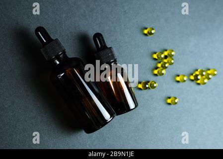 Siero cutaneo idratante e curativo con vitamina C su fondo nero. Capsule di vitamina come supplemento ad una crema o essenza per la cura domestica. Foto Stock