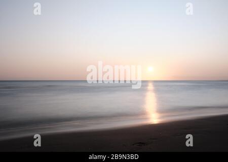 Una lunga vista di impronte umane camminare al tramonto sulla spiaggia di Solanas, Punta Ballena, Maldonado, Uruguay Foto Stock