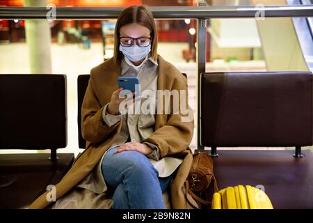 Donna sconvolto sopra la cancellazione del volo, scrive il messaggio alla famiglia, seduto in un terminal quasi vuoto aeroporto a causa di coronavirus pandemic/Covid-19 focolaio Foto Stock