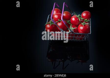 Concetto di supermercato. Primo piano con pomodori freschi. Carrello. Negozio di alimentari. Consegna di pomodori. Vendita al dettaglio e vendita. Pomodori ciliegini. Foto Stock