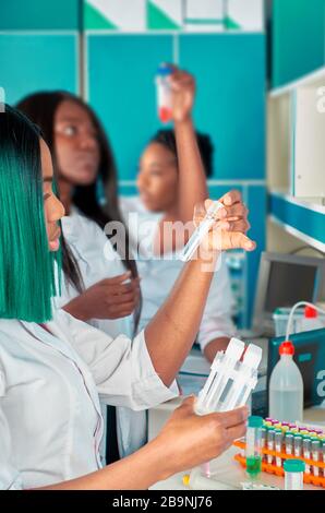 Studentesse mediche africane, giovani laureati in ricerca, laboratori di test medici che eseguono vari test su campioni. Nuovo test antiboody su recuperato Foto Stock
