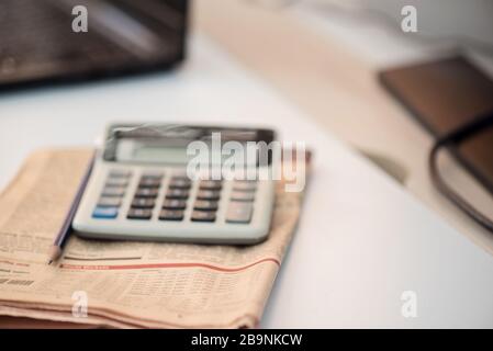 Calcolatrice e giornale finanziario. Concetto di coronavirus. Concetto di lavoro da casa Foto Stock