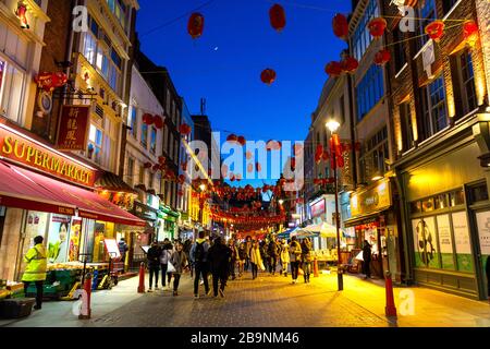 Lanterne cinesi rosse e gialle appese sopra una strada di notte a China Town, Londra, Regno Unito Foto Stock