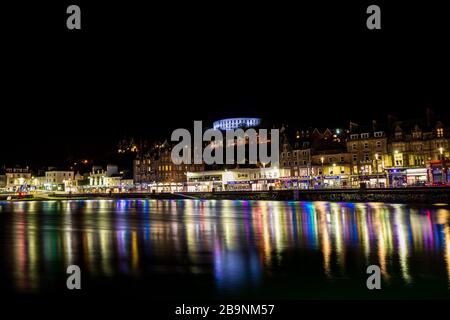 Le luci notturne della città si riflettono nelle acque della città costiera scozzese Oban Foto Stock
