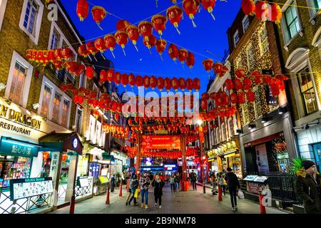 Lanterne cinesi rosse e gialle appese sopra una strada di notte a China Town, Londra, Regno Unito Foto Stock