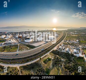 Vista aerea della pianta chimica al tramonto, raffinazione del petrolio, fumo, tubi, inquinamento ecologico, infezione dell'aria, costa del mare in Grecia, petroliere si aspettano Foto Stock