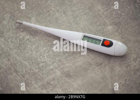 Termometro elettronico da primo piano per la misurazione della temperatura corporea su sfondo grigio Foto Stock