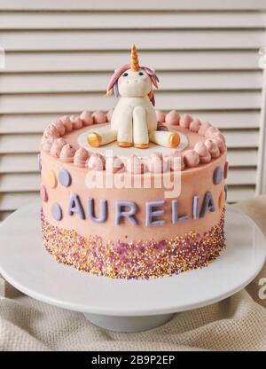 Closeup verticale di una torta di compleanno con un unicorno su La parte superiore e il nome Aurelia su di esso piastra Foto Stock