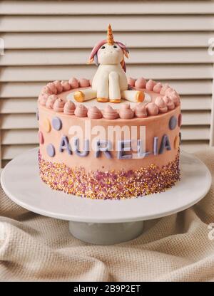 Closeup verticale di una torta di compleanno con un unicorno su La parte superiore e il nome Aurelia su di esso piastra Foto Stock