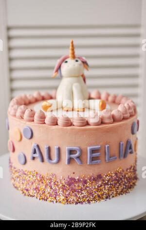 Closeup verticale di una torta di compleanno con un unicorno su La parte superiore e il nome Aurelia su di esso piastra Foto Stock